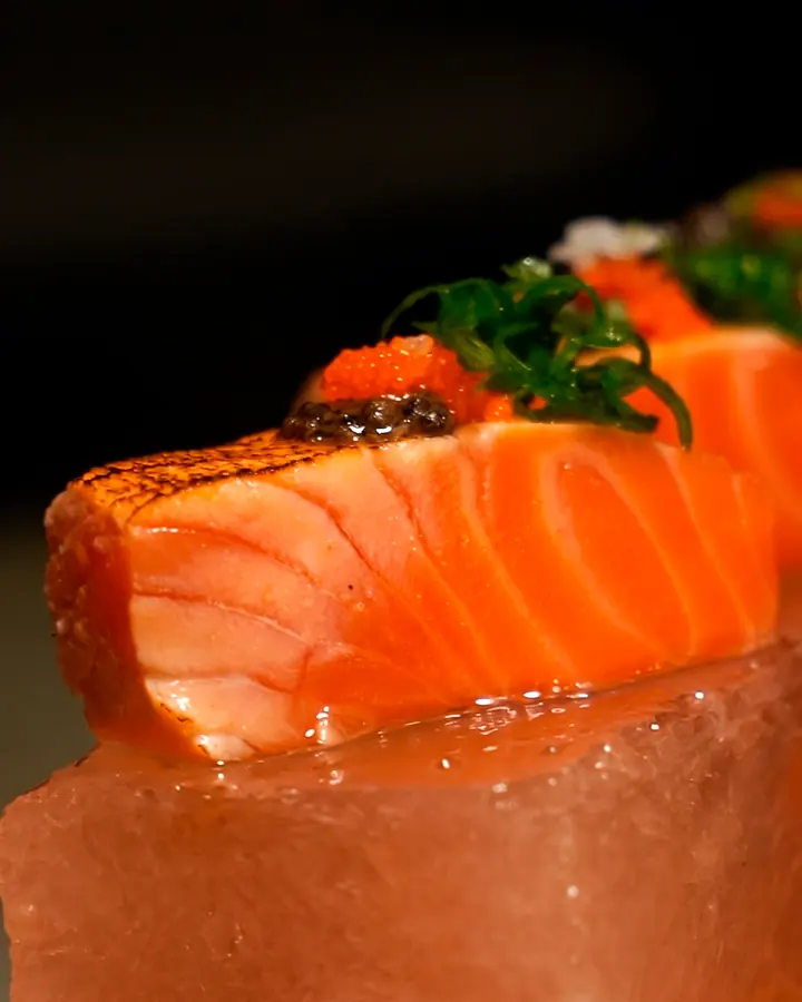 Salmão maçaricado com ovas sobre bloco de sal rosa
